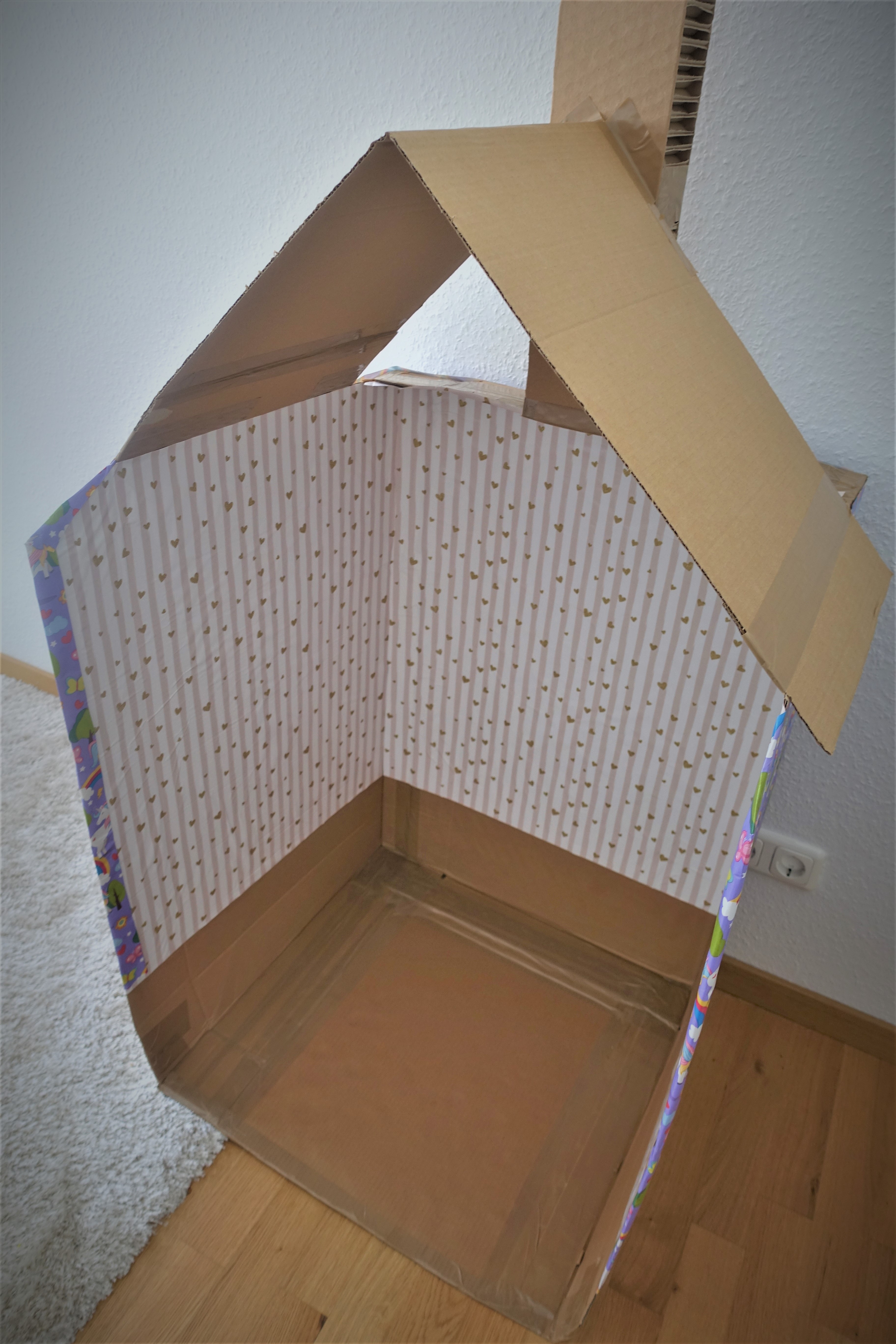 Stacked cardboard to form a small house with a roof and a chimney