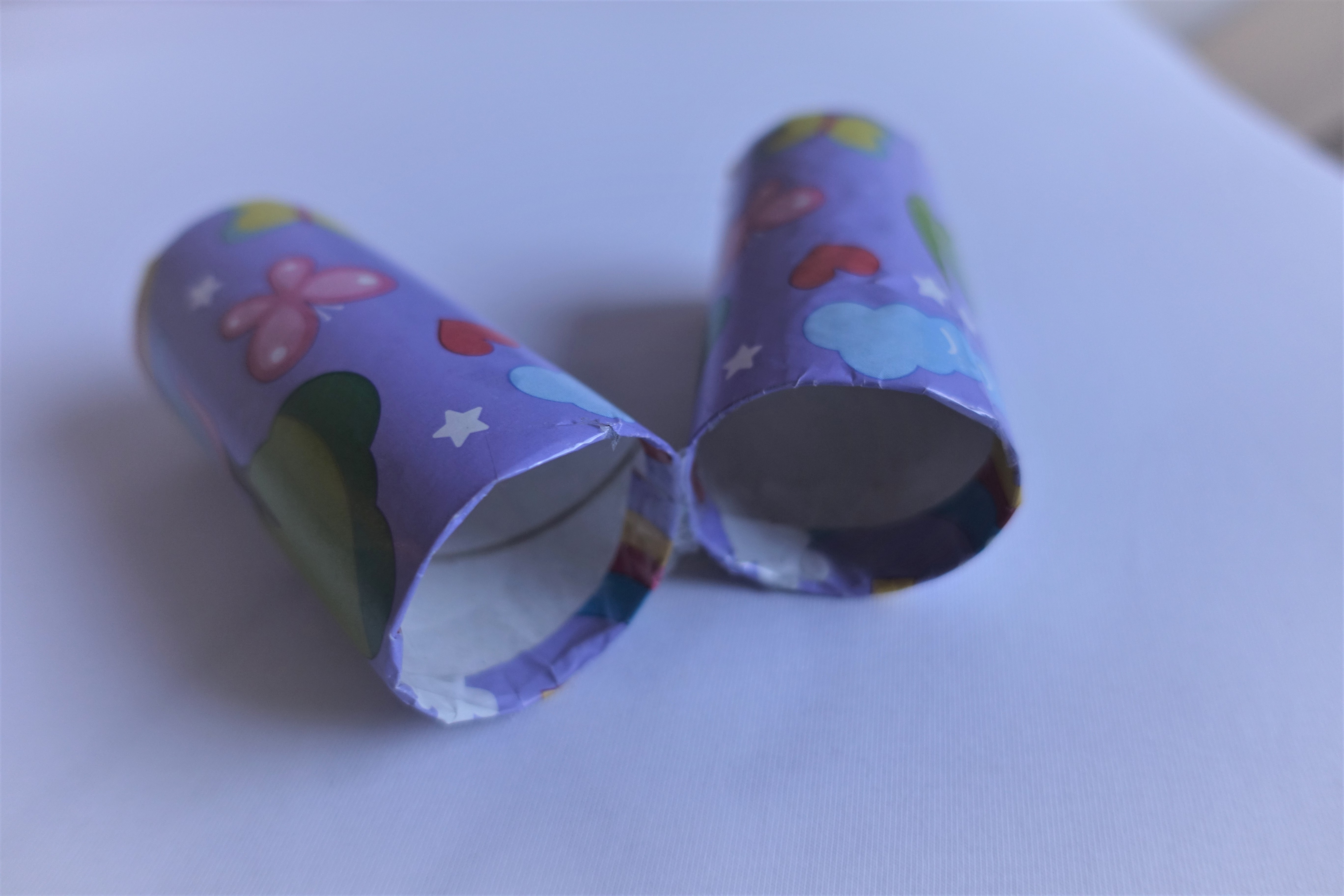 Two toilet paper rolls covered with a purple unicorn wrapping paper