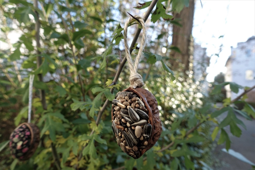 A bird feeder ornament hanging in a tree