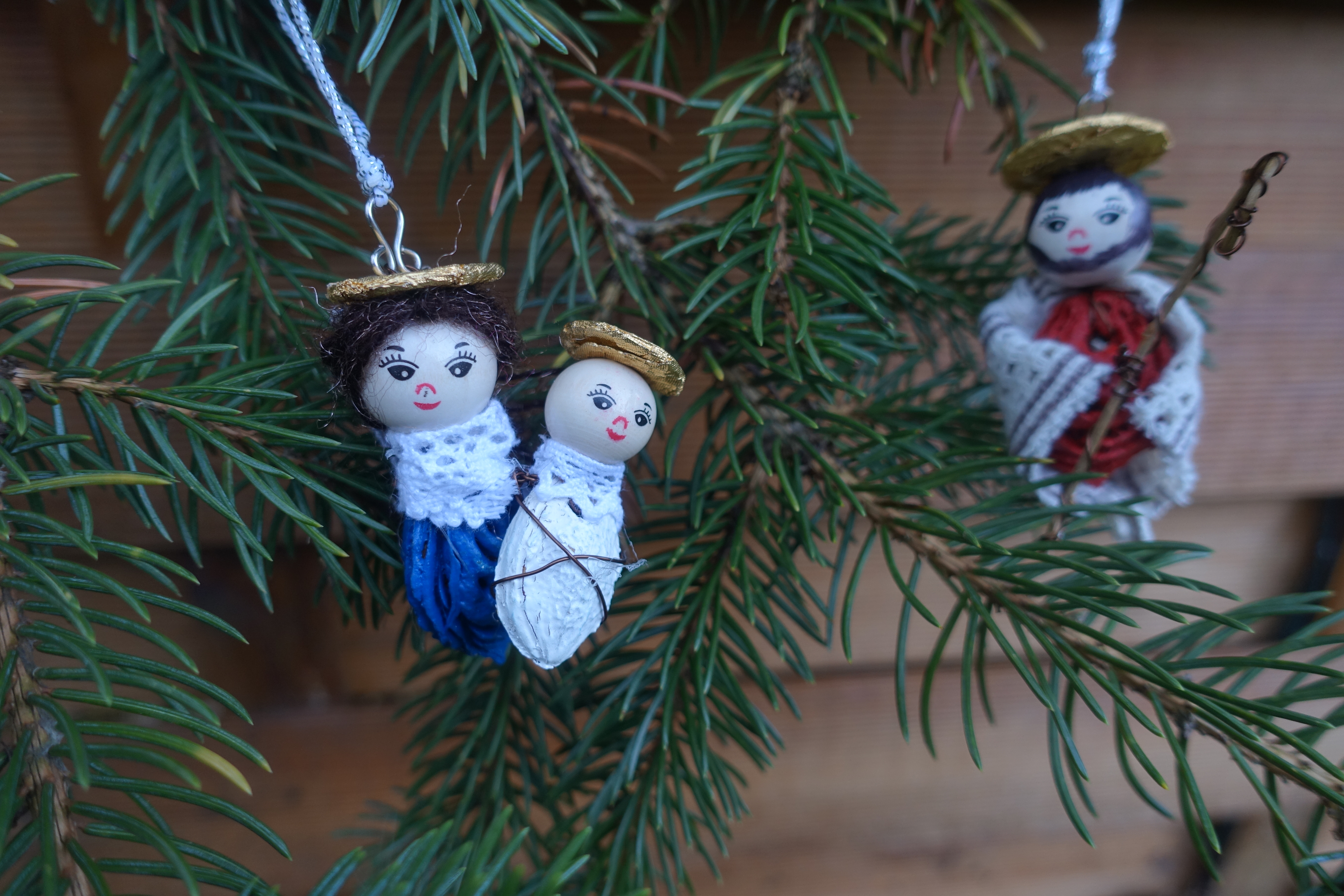 Ornaments of Mary holding Jesus and Joseph hanging on a tree