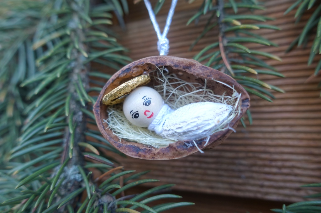Baby Jesus ornament lying in a crip made of walnut
